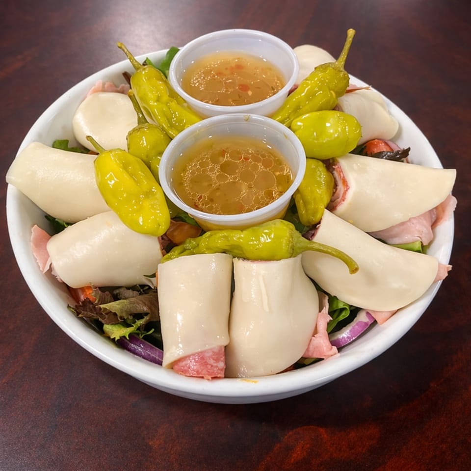 Antipasto salad with rolled provolone and ham, pepperoncini, and two cups of dressing.